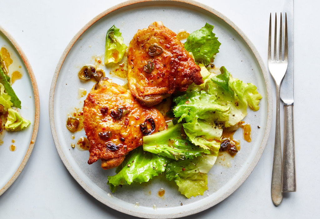 Hot Honey Chicken plated on a white ceramic dish with a glossy sweet-heat glaze, garnished with fresh thyme and chili flakes, served alongside roasted vegetables