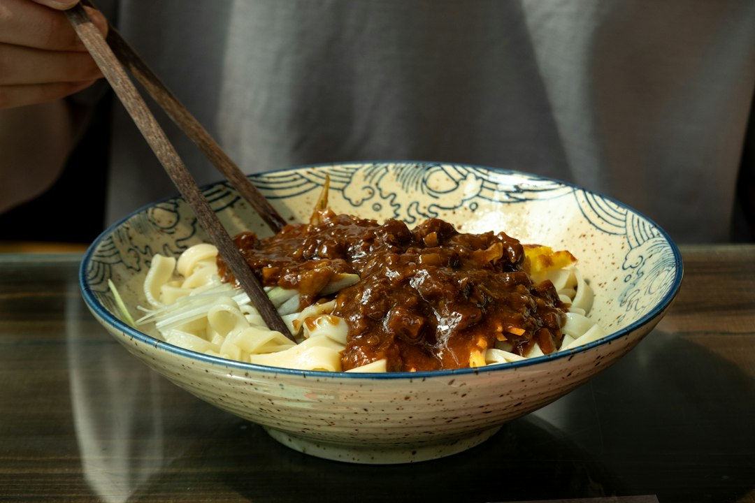 A beautifully plated bowl of Hungarian Goulash with tender beef chunks in a deep red paprika broth, garnished with fresh parsley and served alongside egg noodles, photographed on a rustic wooden table