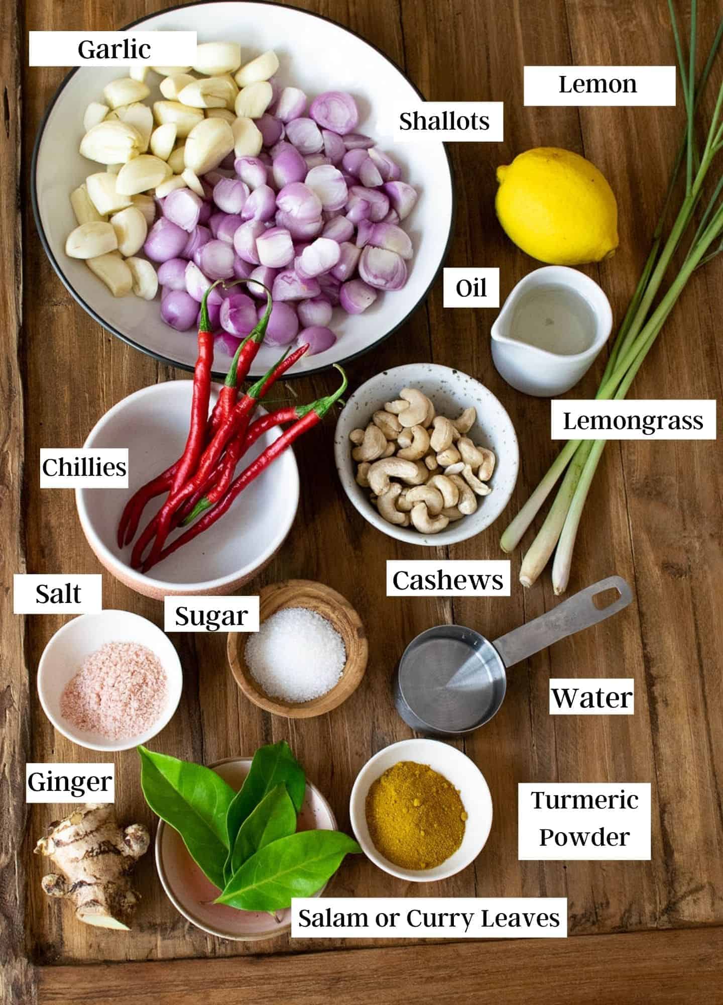 Indonesian Beef ingredients laid out flat on a light marble surface — whole spices, lemongrass stalks, galangal root, coconut milk can, and fresh chilies