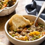 Instant Pot beef stew served in rustic ceramic bowls with fresh herbs and crusty bread, showing tender beef and colorful vegetables in rich broth