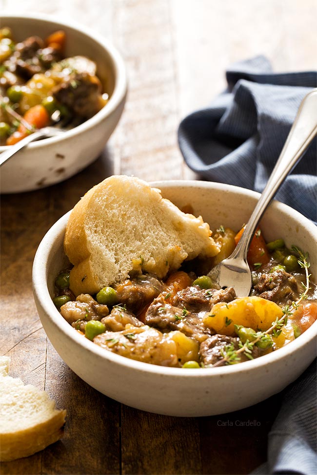 Instant Pot beef stew served in rustic ceramic bowls with fresh herbs and crusty bread, showing tender beef and colorful vegetables in rich broth