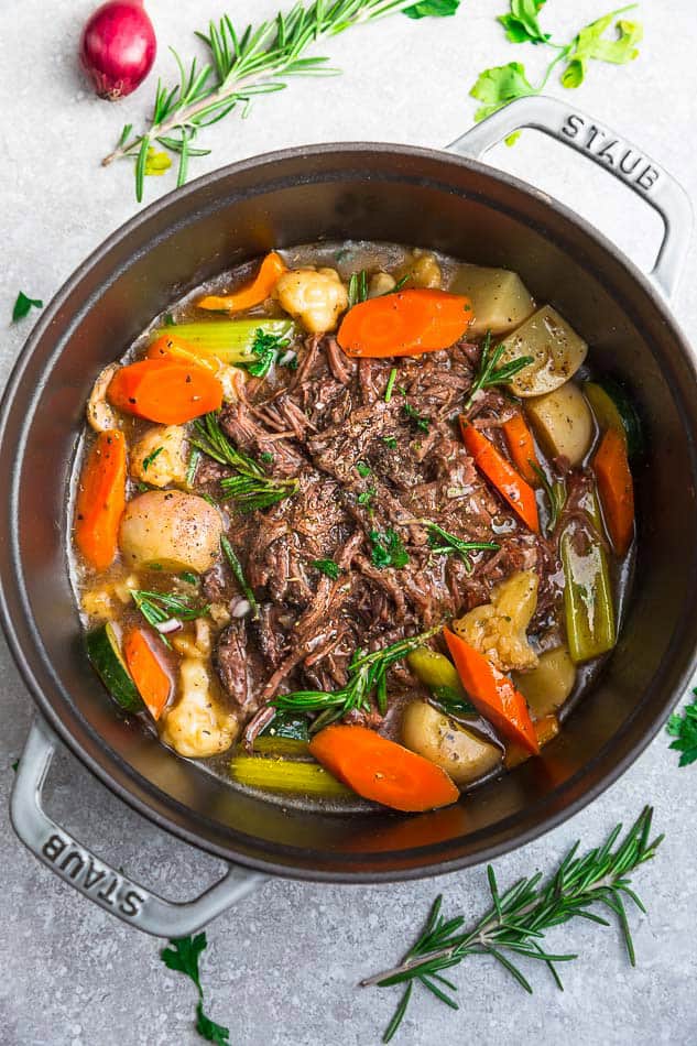 Chunks of beef being seared in the Instant Pot with golden-brown caramelization, alongside prepped vegetables on a cutting board