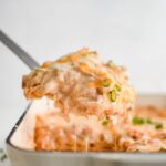 King Ranch Chicken Casserole served in a white baking dish with bubbling cheese and fresh cilantro garnish on a rustic wooden table