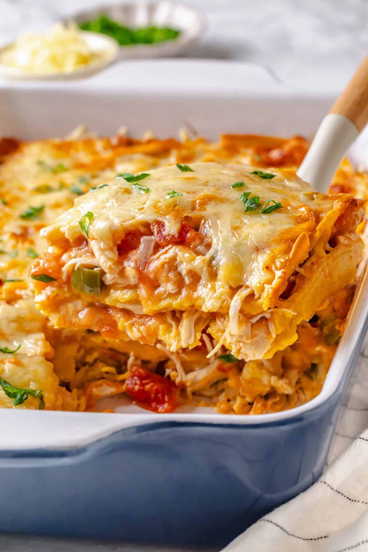 Close-up of a serving of King Ranch Chicken Casserole being lifted with a spatula, showing the melted cheese pull and layered tortillas underneath