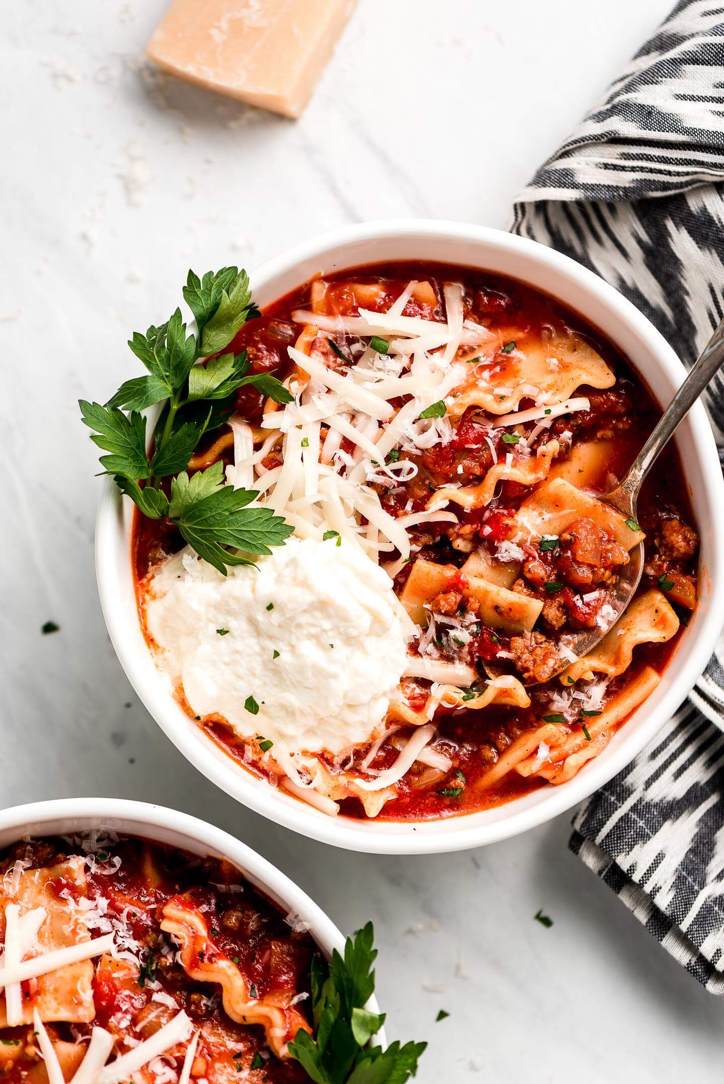 Lasagna Soup — All the Comfort of Lasagna in One Cozy Bowl 27 A flat lay of lasagna soup ingredients including crushed San Marzano tomatoes, broken lasagna noodles, ground beef, Italian sausage, fresh garlic, onion, ricotta cheese, and fresh basil on a white marble surface