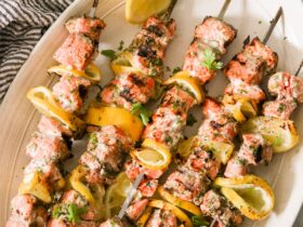 lemon garlic salmon skewers beautifully plated on a white serving board with lemon slices and fresh parsley garnish