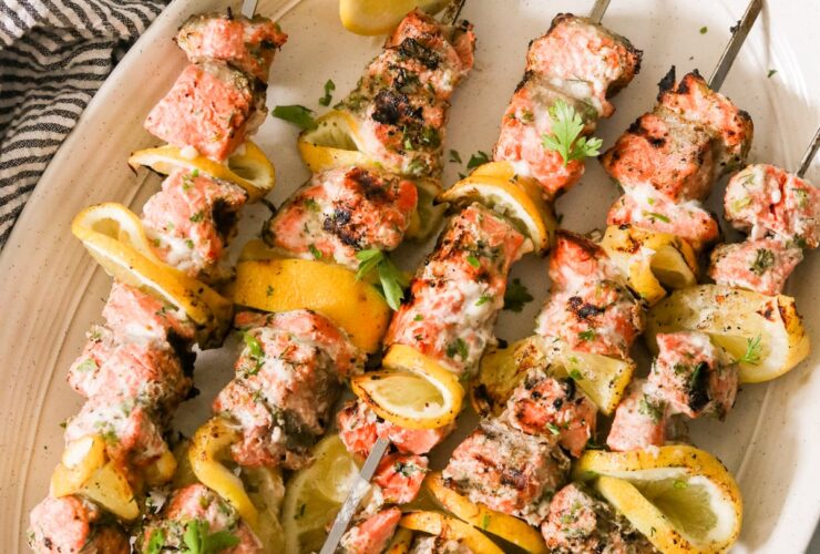 lemon garlic salmon skewers beautifully plated on a white serving board with lemon slices and fresh parsley garnish