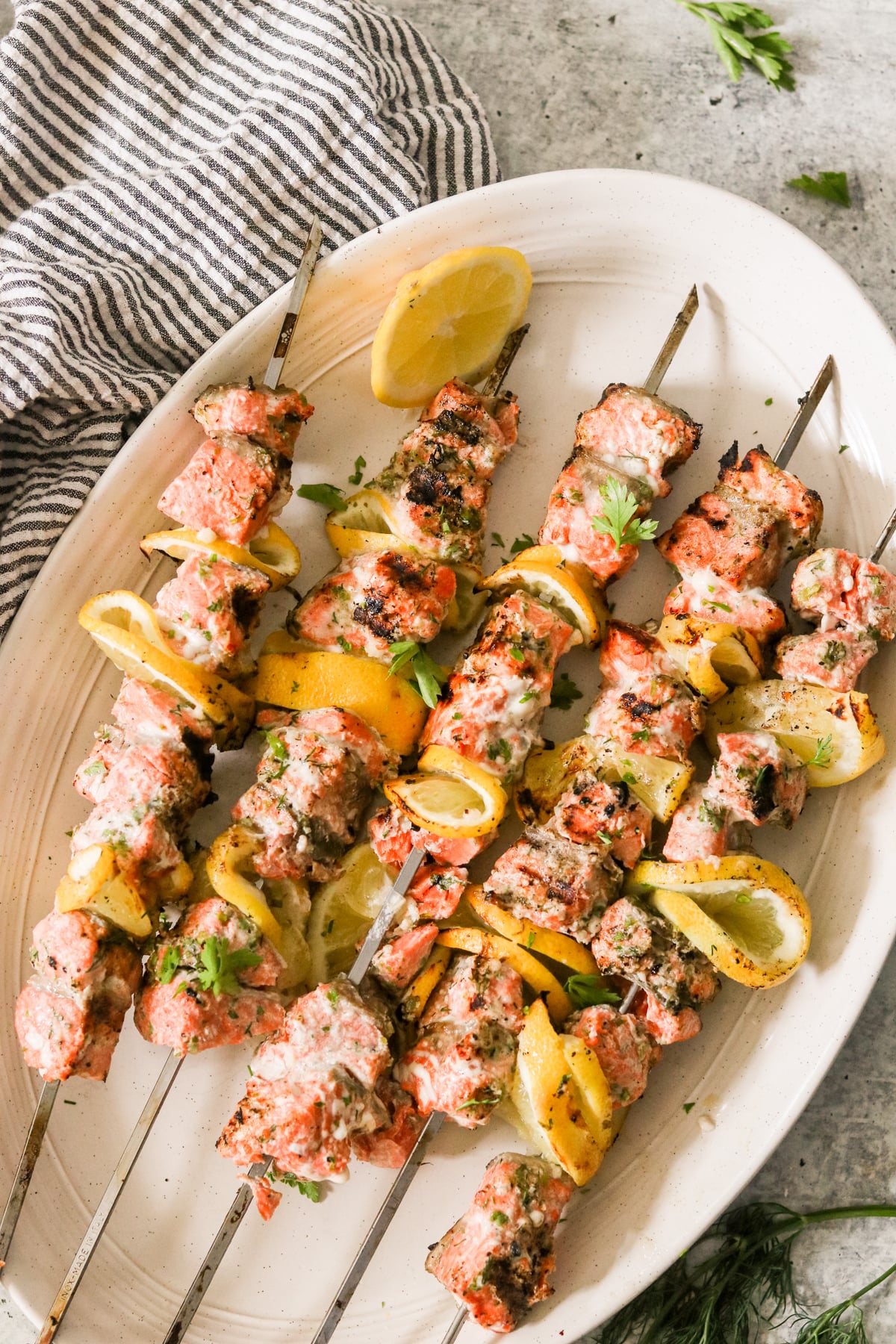 Lemon Garlic Salmon Skewers — Bright, Bold, and Ready in 30 Minutes 27 raw salmon cubes, lemon halves, garlic cloves, parsley, Dijon mustard, and olive oil arranged on a marble surface as an ingredients flat lay
