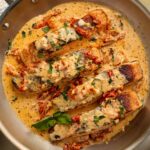 Marry Me Salmon fillets plated in a creamy sun-dried tomato cream sauce garnished with fresh basil and parmesan in a cast iron skillet