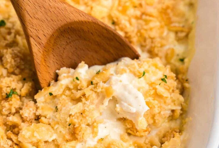 Million dollar chicken casserole in a white baking dish, golden buttery cracker topping, steam rising, beautifully plated on a wooden table