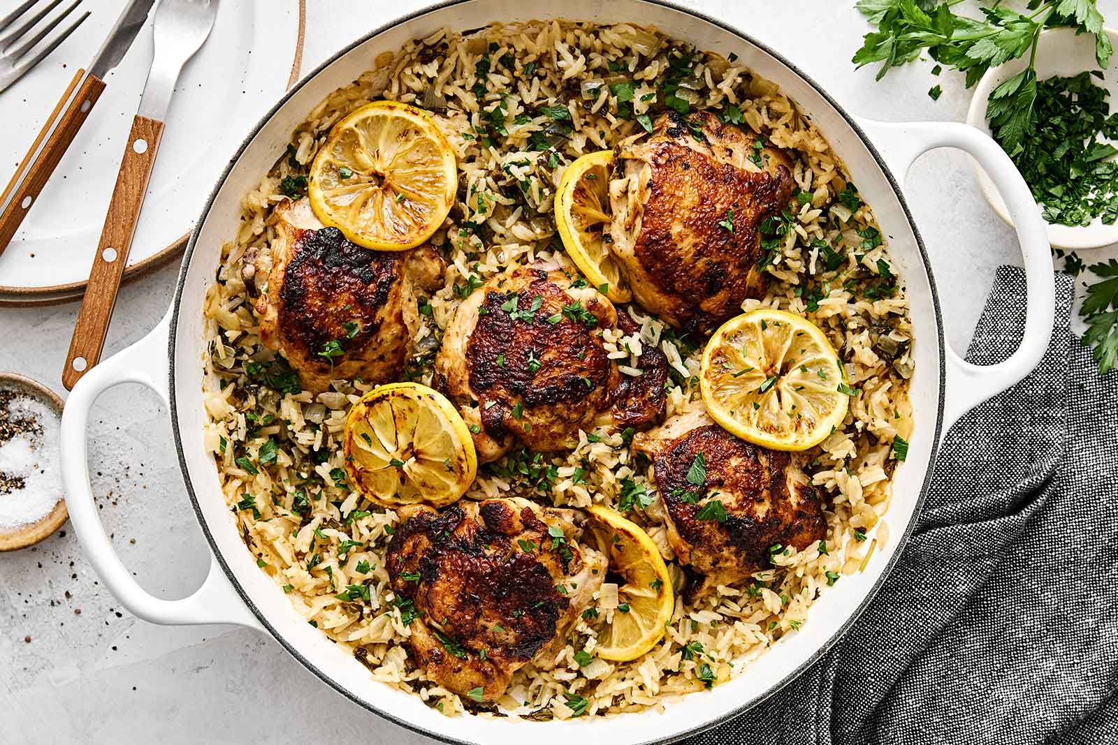 One Pan Chicken and Rice — The Easy, Nourishing Weeknight Dinner That Does It All 26 One Pan Chicken and Rice served in a cast iron skillet, garnished with fresh parsley and lemon wedges, golden chicken thighs resting on fluffy seasoned rice