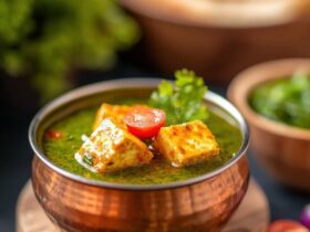 Palak Paneer served in a copper bowl, vibrant green spinach curry with golden paneer cubes, garnished with cream and fresh ginger, overhead shot on a warm wooden surface