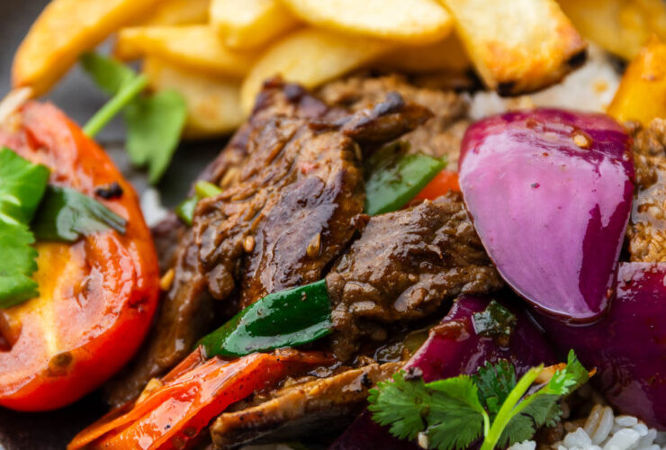 Peruvian Lomo Saltado — A Bold, Nourishing Stir-Fry You'll Make on Repeat 27 Peruvian Lomo Saltado plated beautifully in a wide bowl with golden french fries, tender beef strips, vibrant tomatoes and red onions, garnished with fresh cilantro