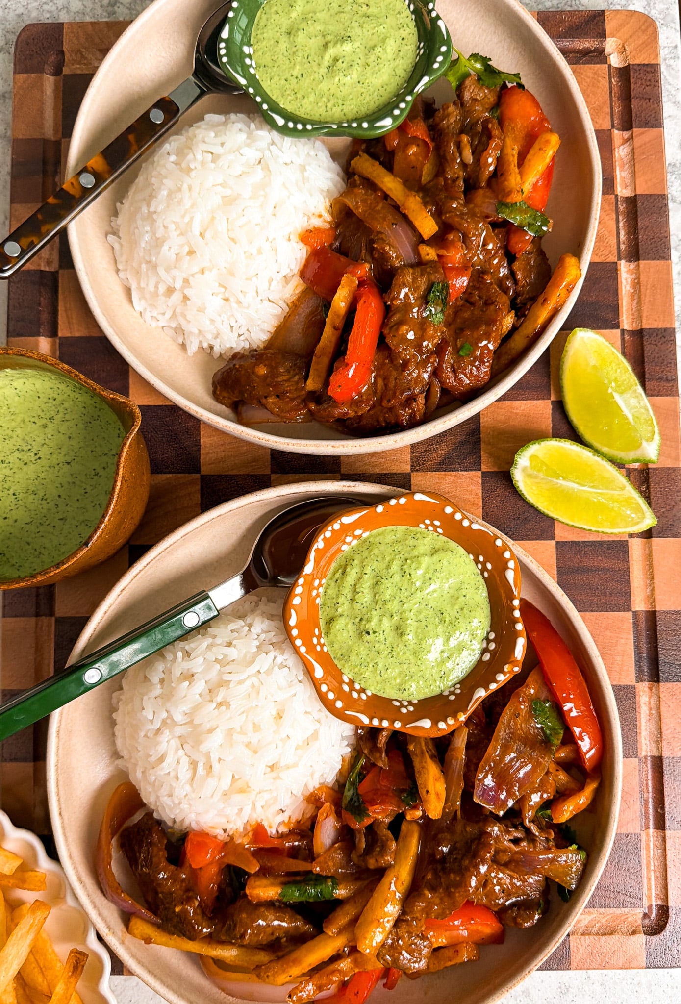 Close-up of Peruvian Lomo Saltado served in a white bowl with fluffy white rice, showing the glossy soy sauce coating on the beef strips, vibrant tomatoes, and a sprig of fresh cilantro on top