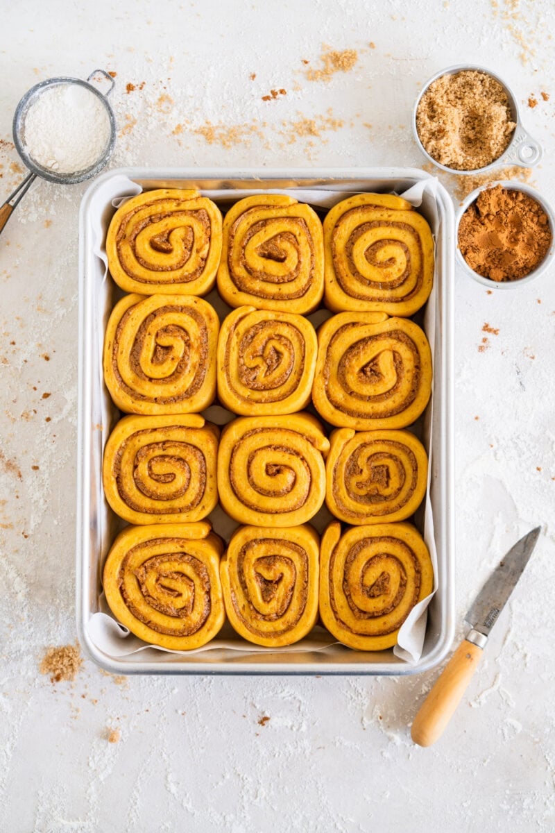 Pumpkin Cinnamon Rolls with Cream Cheese Maple Icing — The Ultimate Overnight Fall Treat 27 Overhead flat-lay of pumpkin cinnamon roll ingredients — bread flour, canned pumpkin purée, brown sugar, cinnamon, cream cheese, maple syrup, eggs, and butter arranged on a marble surface