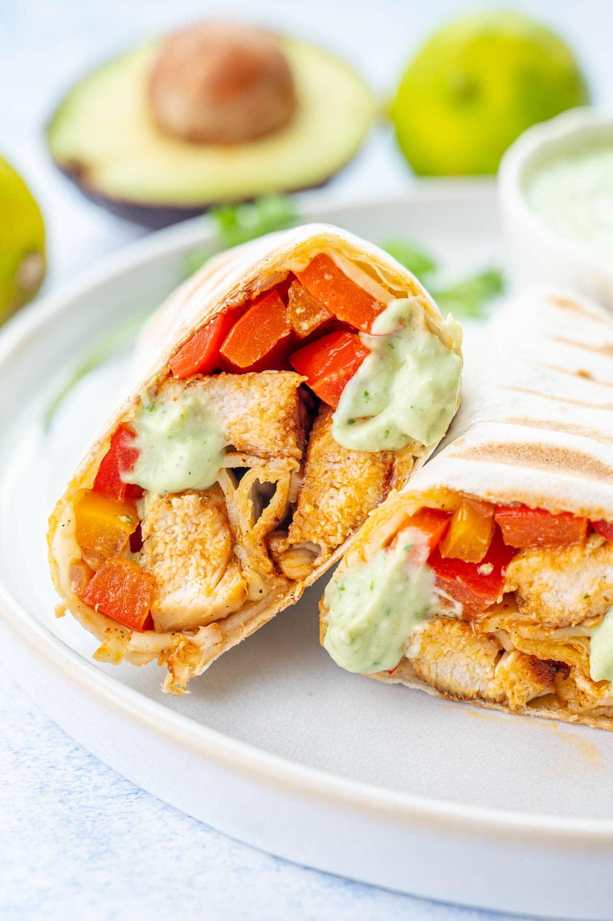 Sheet Pan Chicken Fajitas — The Easy, Healthy One-Pan Taco Night Winner 28 Close-up of a hand-held chicken fajita wrap stuffed with roasted peppers, chicken strips, avocado slices, and a squeeze of fresh lime juice, with colorful pan filling blurred in the background