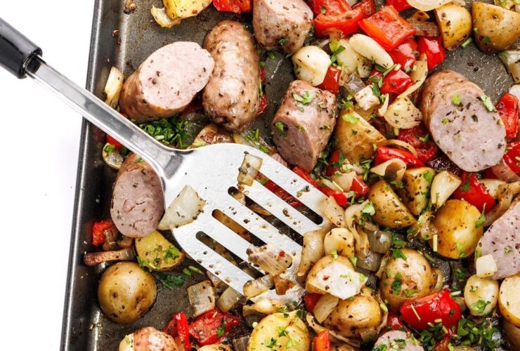 Sheet pan sausage and peppers with roasted potatoes and onions on a large baking sheet, golden and caramelized, garnished with fresh parsley