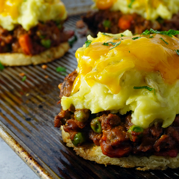 Classic Shepherd's Pie in a white ceramic baking dish with golden mashed potato crust, freshly pulled from the oven on a rustic wood table