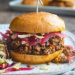 Classic homemade Sloppy Joes served on toasted brioche buns with a side of coleslaw, photographed on a rustic wooden board