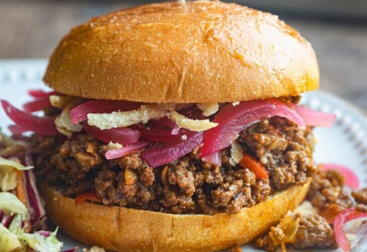 Classic homemade Sloppy Joes served on toasted brioche buns with a side of coleslaw, photographed on a rustic wooden board