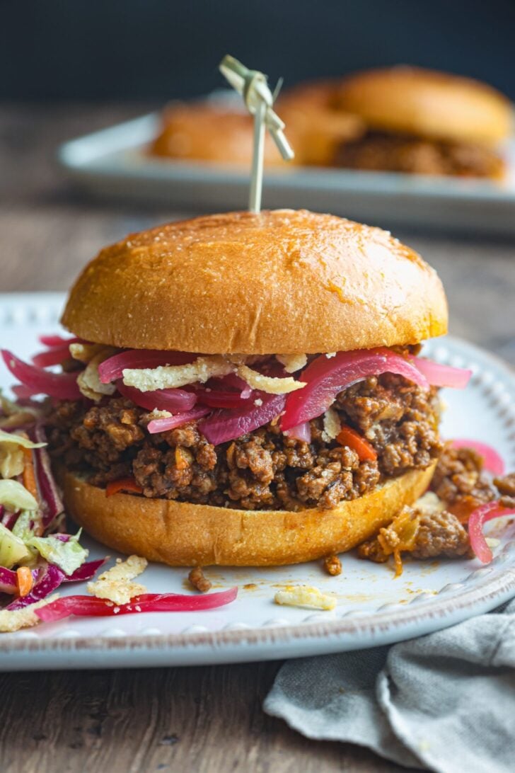 Classic homemade Sloppy Joes served on toasted brioche buns with a side of coleslaw, photographed on a rustic wooden board
