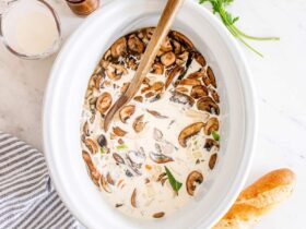 Slow cooker chicken wild rice soup served in a rustic white bowl, garnished with fresh thyme, steam rising, on a wooden table with a cozy linen napkin