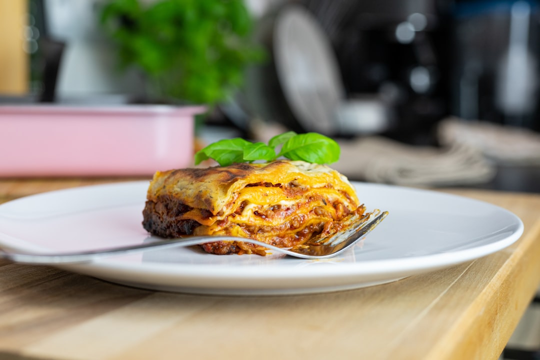 Close-up of a slice of slow cooker lasagna being lifted from the crock with a spatula, showing cheesy layers and rich meat sauce