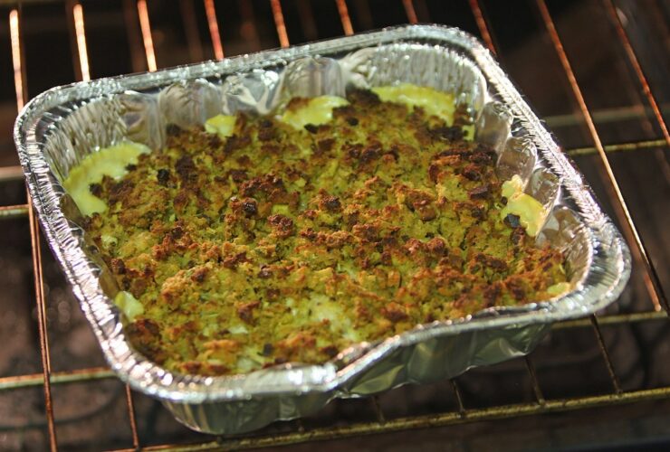 Golden tater tot casserole fresh from the oven in a white baking dish, topped with melted cheddar cheese and crispy tots, garnished with fresh parsley on a rustic wooden table