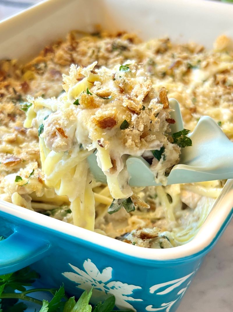 Tuna Casserole — The Classic Comfort Dish Made with Clean, Wholesome Ingredients 26 Creamy tuna casserole in a white baking dish with a golden breadcrumb topping, fresh parsley garnish, and a serving spoon resting on the side