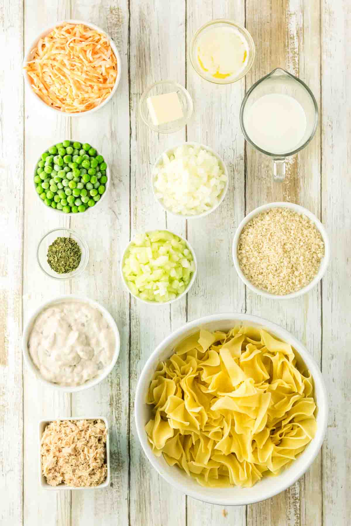 Tuna Casserole — The Classic Comfort Dish Made with Clean, Wholesome Ingredients 27 Overhead flat lay of tuna casserole ingredients including canned albacore tuna, egg noodles, shredded cheddar, frozen peas, panko breadcrumbs, onion, and fresh herbs arranged on a light linen surface