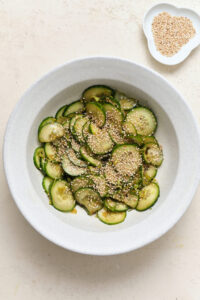 Viral Cucumber Salad — The Crunchy, Tangy Recipe Taking Over the Internet 13 viral cucumber salad served in a white bowl with sesame seeds, chili flakes, and fresh herbs on a light marble surface