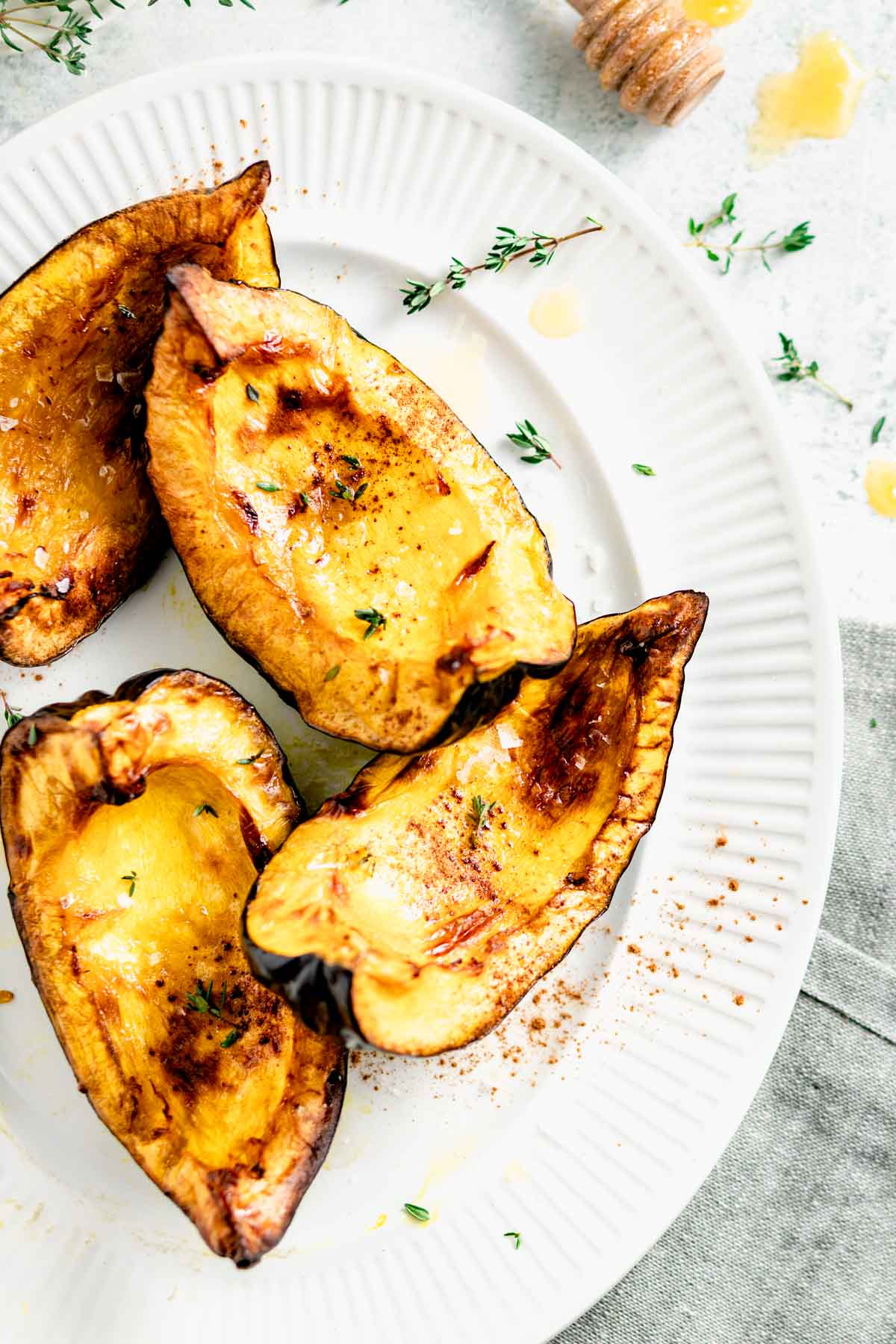 Air fryer acorn squash wedges with maple-cinnamon glaze and Greek yogurt drizzle on a rustic wooden board, garnished with fresh thyme and a drizzle of maple syrup