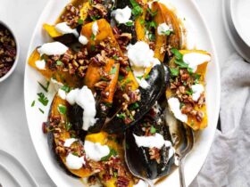 Air Fryer Acorn Squash with Maple-Cinnamon Glaze & Greek Yogurt Drizzle 17 Close-up of a single air fryer acorn squash wedge with caramelized maple glaze, drizzled with white Greek yogurt sauce and sprinkled with cinnamon, on a dark ceramic plate