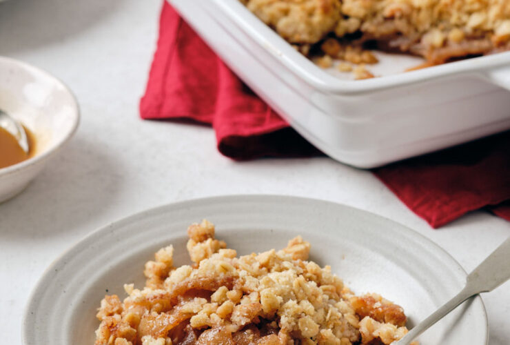Flat-lay of all key ingredients for greek yogurt apple crisp — sliced apples, rolled oats, sliced almonds, butter cubes, cinnamon sticks, maple syrup, and a bowl of thick Greek yogurt on a marble surface