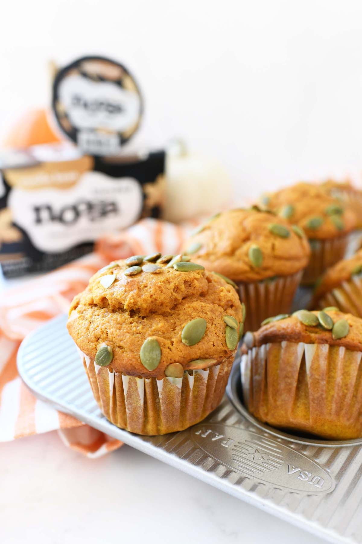 Greek Yogurt Pumpkin Muffins — Moist, Wholesome & Naturally Sweet 10 Greek yogurt pumpkin muffins stacked on a wooden board with a cozy autumn backdrop, dusted with cinnamon