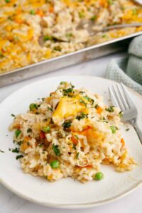 Healthier Chicken and Rice Casserole — Creamy, Comforting & Clean 13 Healthier chicken and rice casserole in a white baking dish, golden top, steam rising, fresh parsley garnish on a wooden table