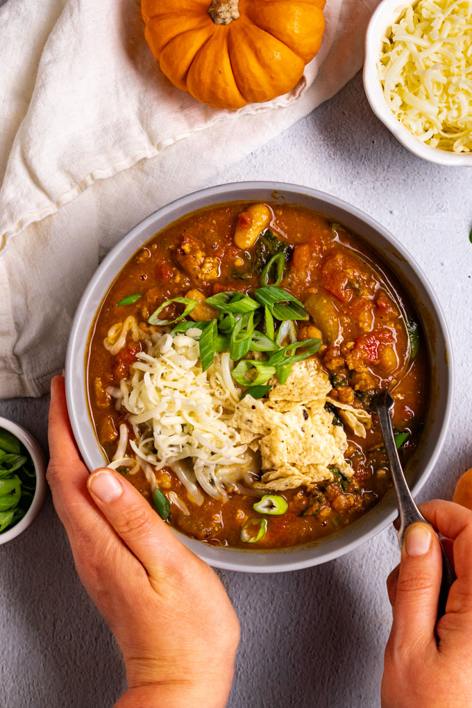 Overhead flat-lay of lean turkey pumpkin chili ingredients including raw ground turkey, a can of pumpkin puree, black beans, diced tomatoes, and small bowls of chili spices