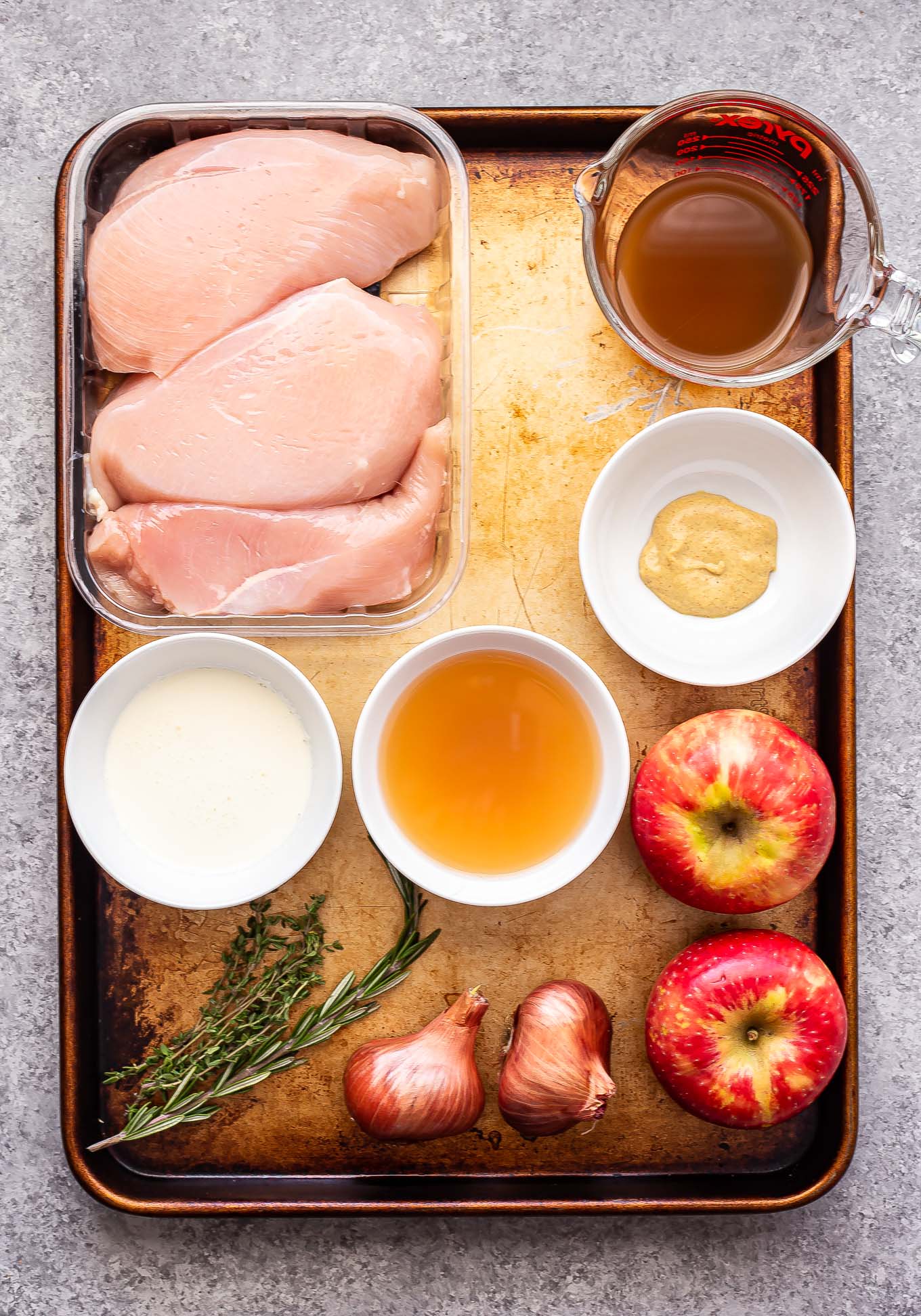Lighter Apple Cider Chicken Skillet — A Wholesome Fall Dinner Ready in 35 Minutes 11 Ingredients for lighter apple cider chicken laid out on a wooden board — chicken breasts, apple cider, fresh thyme, sliced apples, shallots, and garlic