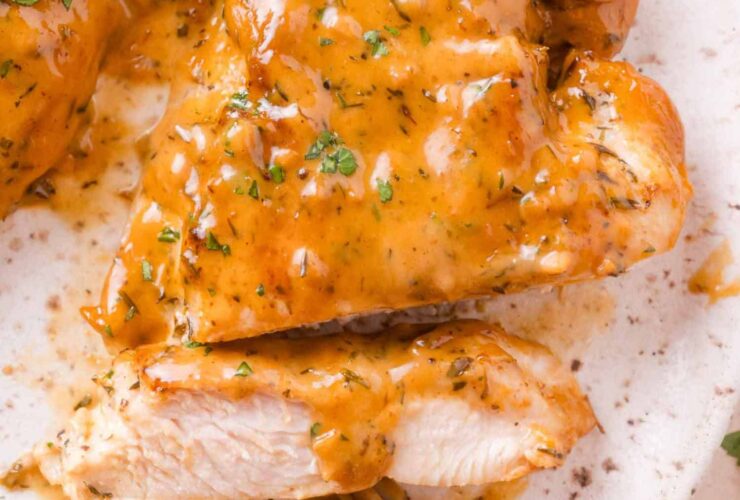 Close-up of lighter apple cider chicken sliced and plated over farro with apple slices and a drizzle of cider pan sauce