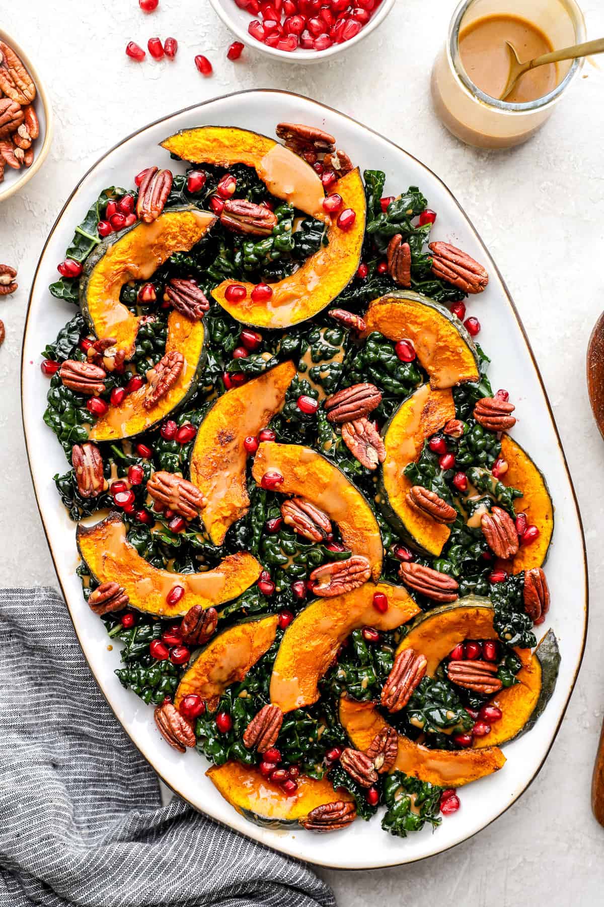 close-up of lighter autumn harvest salad showing pomegranate arils glistening on massaged kale and golden roasted butternut squash with maple-dijon dressing drizzled over the top