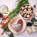 Trimmed lean chuck roast surrounded by colorful root vegetables, fresh herbs, and low-sodium broth in a Dutch oven before braising