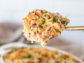 Lighter chicken broccoli rice casserole baked golden in a white ceramic baking dish, garnished with fresh parsley, served on a wooden table