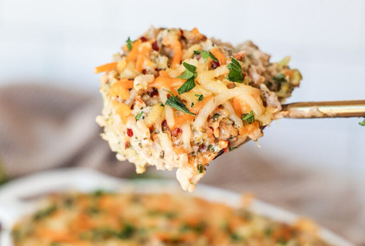 Lighter chicken broccoli rice casserole baked golden in a white ceramic baking dish, garnished with fresh parsley, served on a wooden table