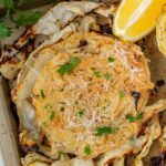 Roasted cabbage steaks on a sheet pan with crispy golden edges, drizzled with olive oil and garnished with fresh parsley