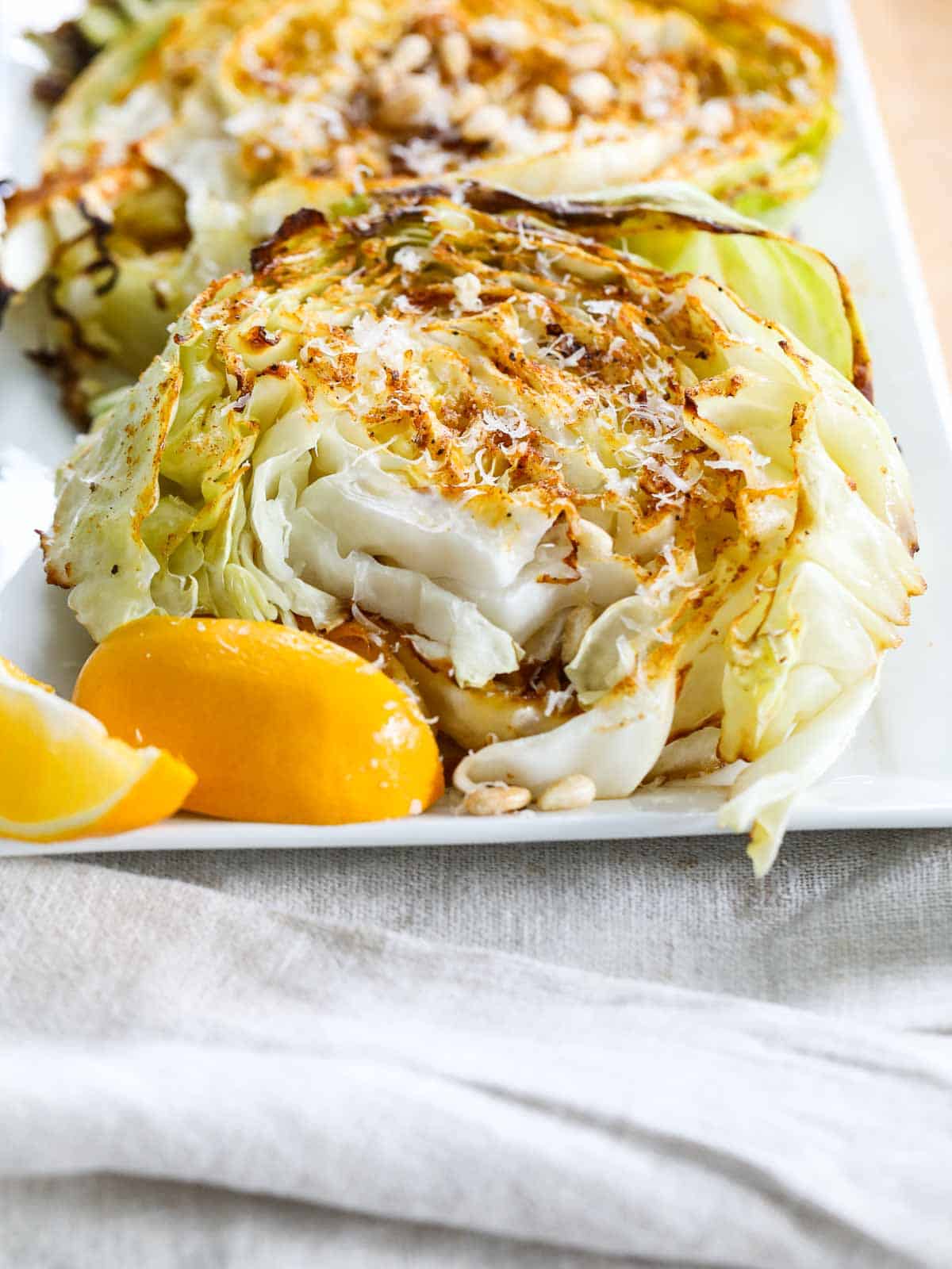 Roasted Cabbage Steaks — Crispy-Edged, Caramelized & Surprisingly Addictive 28 Close-up of a single roasted cabbage steak on a white plate with caramelized golden edges, topped with fresh parsley and a lemon wedge on the side