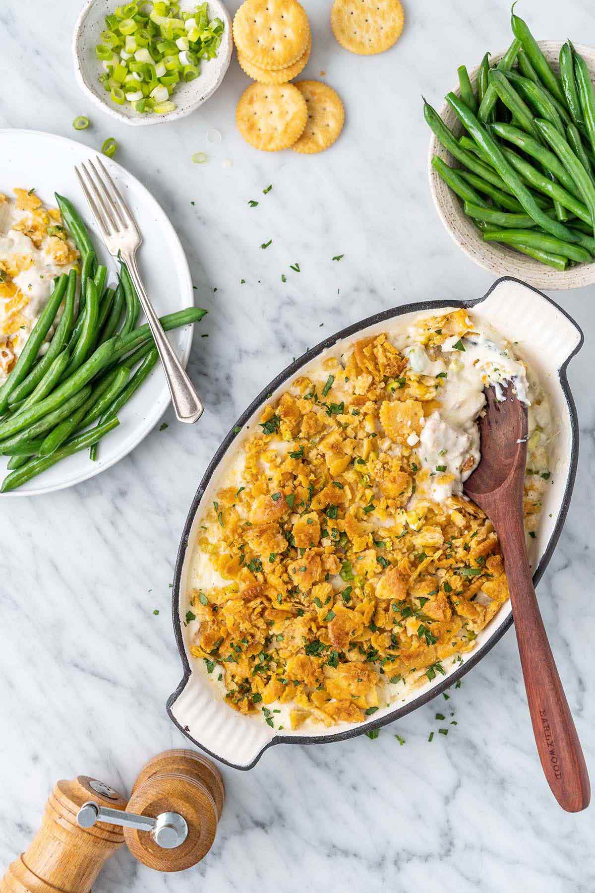 Slow cooker million dollar chicken casserole served in a white bowl topped with golden buttery Ritz cracker crumble, garnished with fresh parsley, shot on a warm wooden table